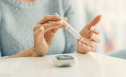 Mature woman doing blood sugar test at home in a living room  Selective focus to her finger 