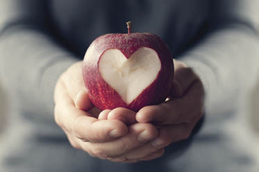 A person holding a red apple in their hands There is a heart carved out of the apple  Change Makers  food