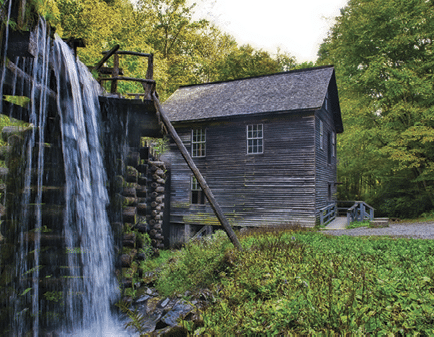 Mingus Mill in Great Smoky Mountain National Park with water pouring over the elevated slough which carries water to the turbine  This mill was a commercial mill and ground grain with a turbine  The turbine is not visible in this picture or to the visitor as it is encased in a large pipe 