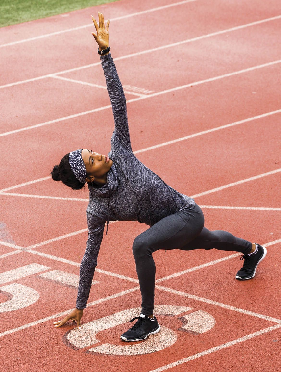 Black woman stretching on track starting line