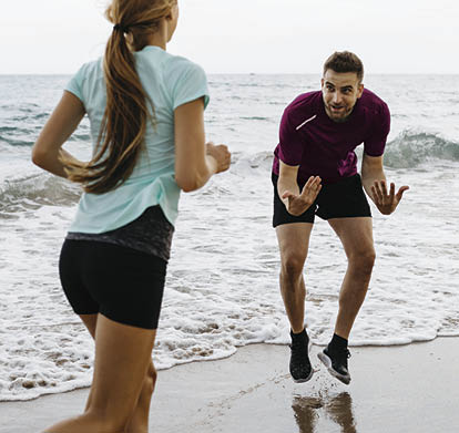 Female jogger on the beach with her coach