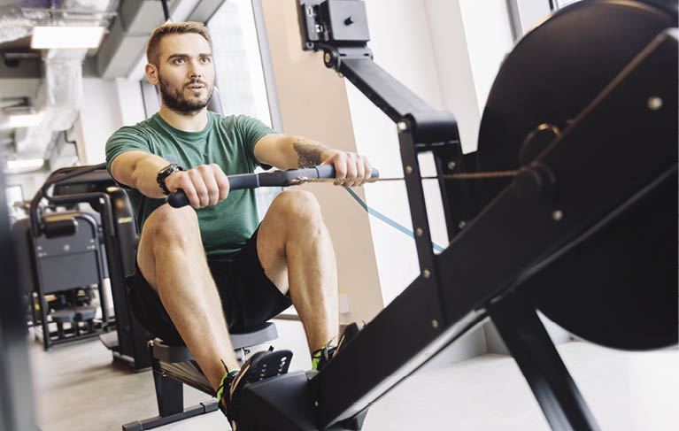 Active athlete man doing his rowing workout in a gym  Fit lifestyle 