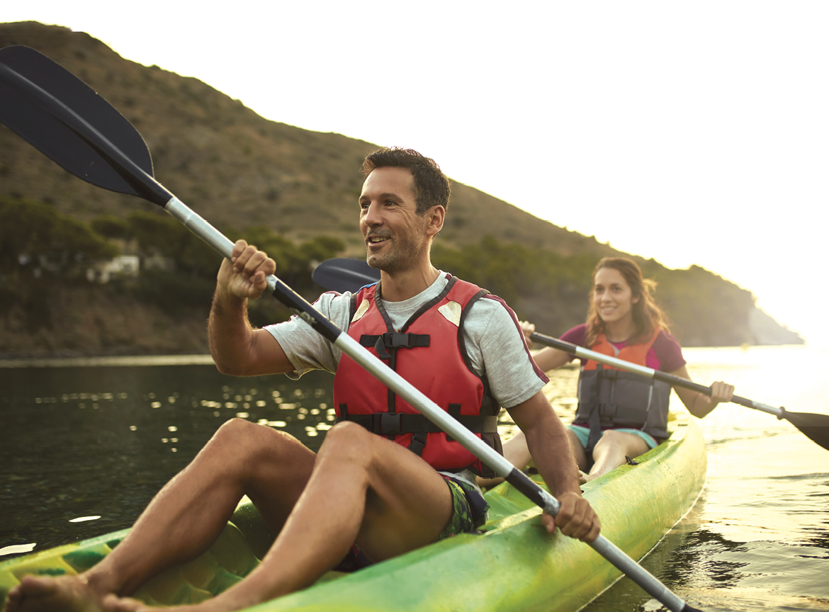 Close-up of active Spanish couple paddling tandem kayak off the Costa Brava in Mediterranean Sea at dawn 