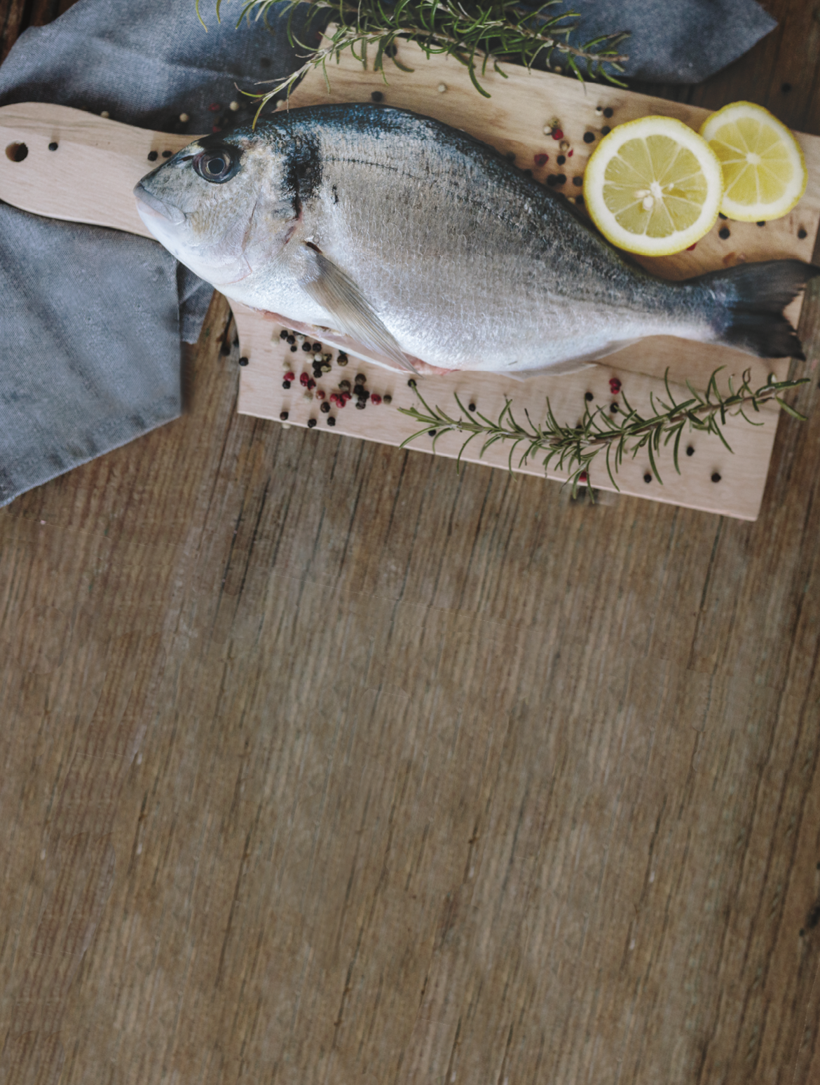 Sea Bream on a wooden board with pepper and rosemary