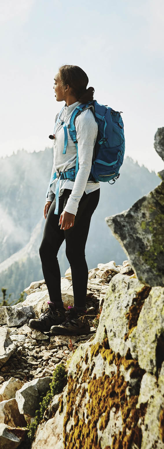 Young woman enjoying view from outlook during hike in mountains