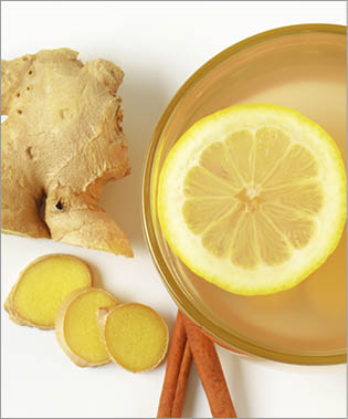 cup of ginger tea with lemon  fresh ginger root and cinnamon sticks on white background