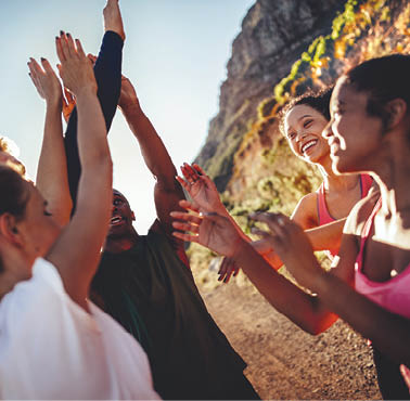 Multi-ethnical group of young adult runners cheering and high fiving after a good run outdoors