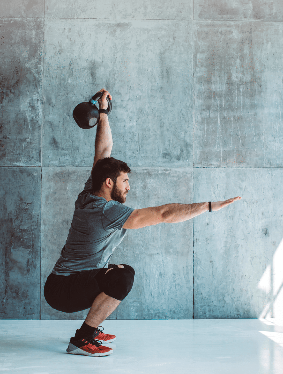 Male fitness athlete performing overhead squat with kettlebell; cross training;