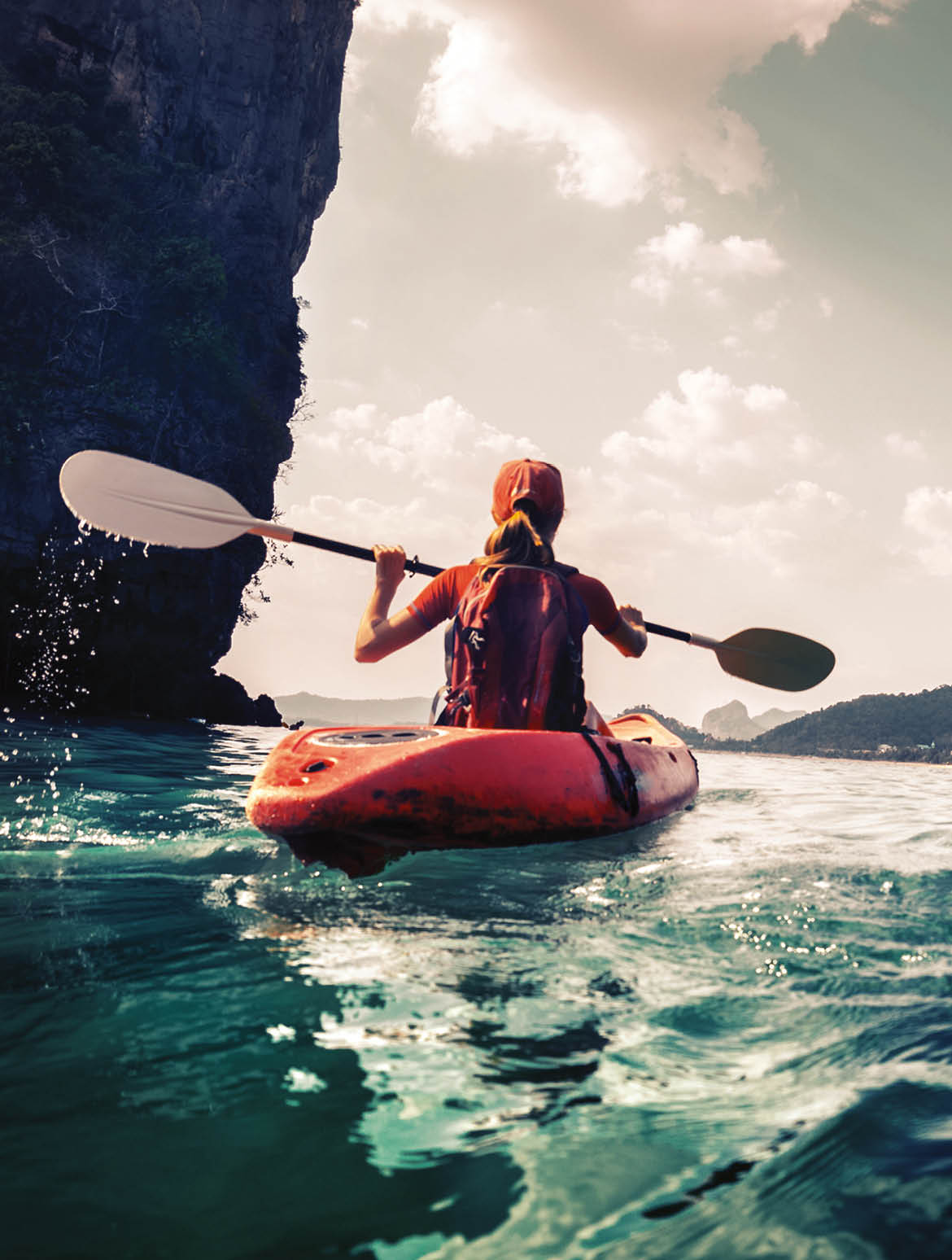 Lady paddling the kayak in the calm tropical bay