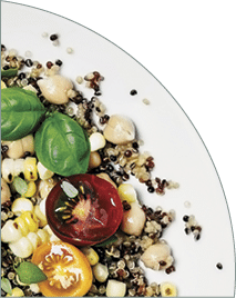 A bowl of quinoa salad  two spoons  and a salt shaker on white background