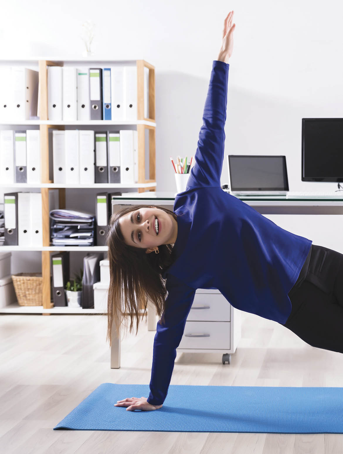 Young Businesswoman Doing Stretching Exercise On Exercise Mat At Workplace