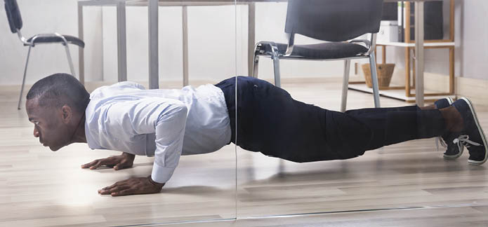 Young African American Man Doing Pushup In Front Of Closed Glass Door