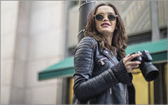 Young beautiful women photographer holding a camera while walking on the street