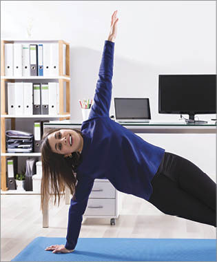 Young Businesswoman Doing Stretching Exercise On Exercise Mat At Workplace