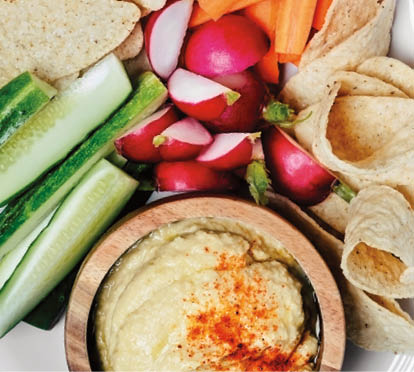 A plate of vegetables and a bowl of hummus on white background