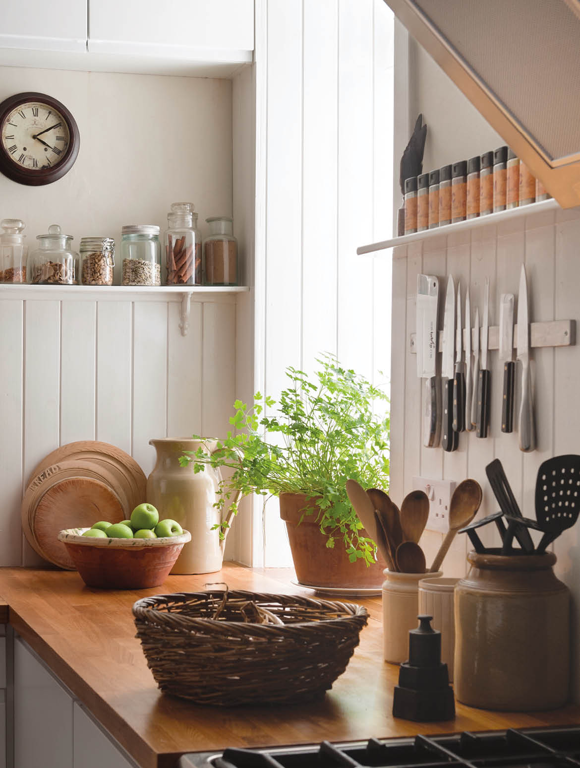 Open shelving and solid oak work surfaces in kitchen with white wooden wall panels