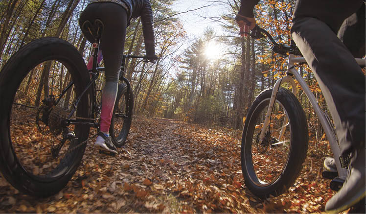 Couple riding fatbikes on trails in the fall