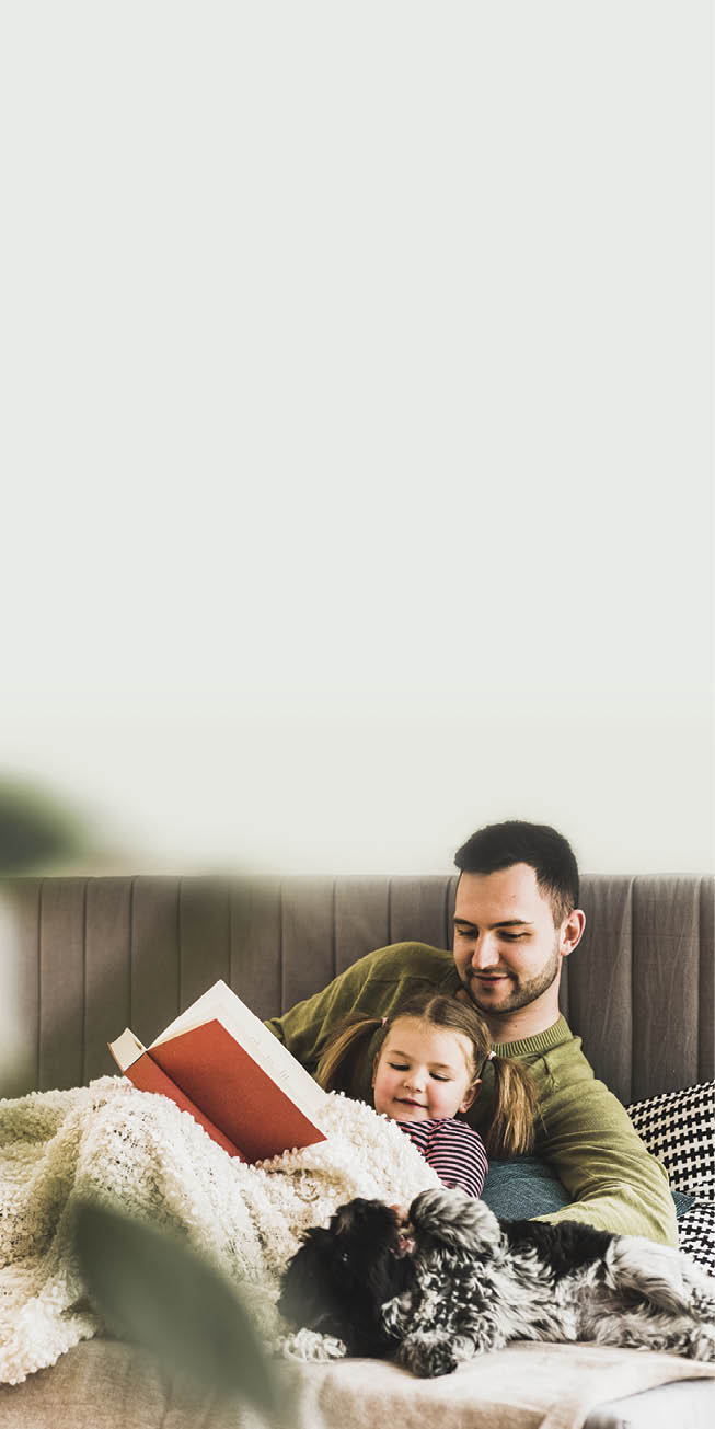 Father and daughter with dog reading a book at home