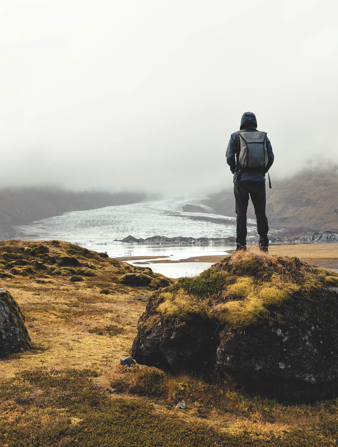 Backpacker standing on the rock and enjoying the view on Vatnajokull glacier in Iceland 