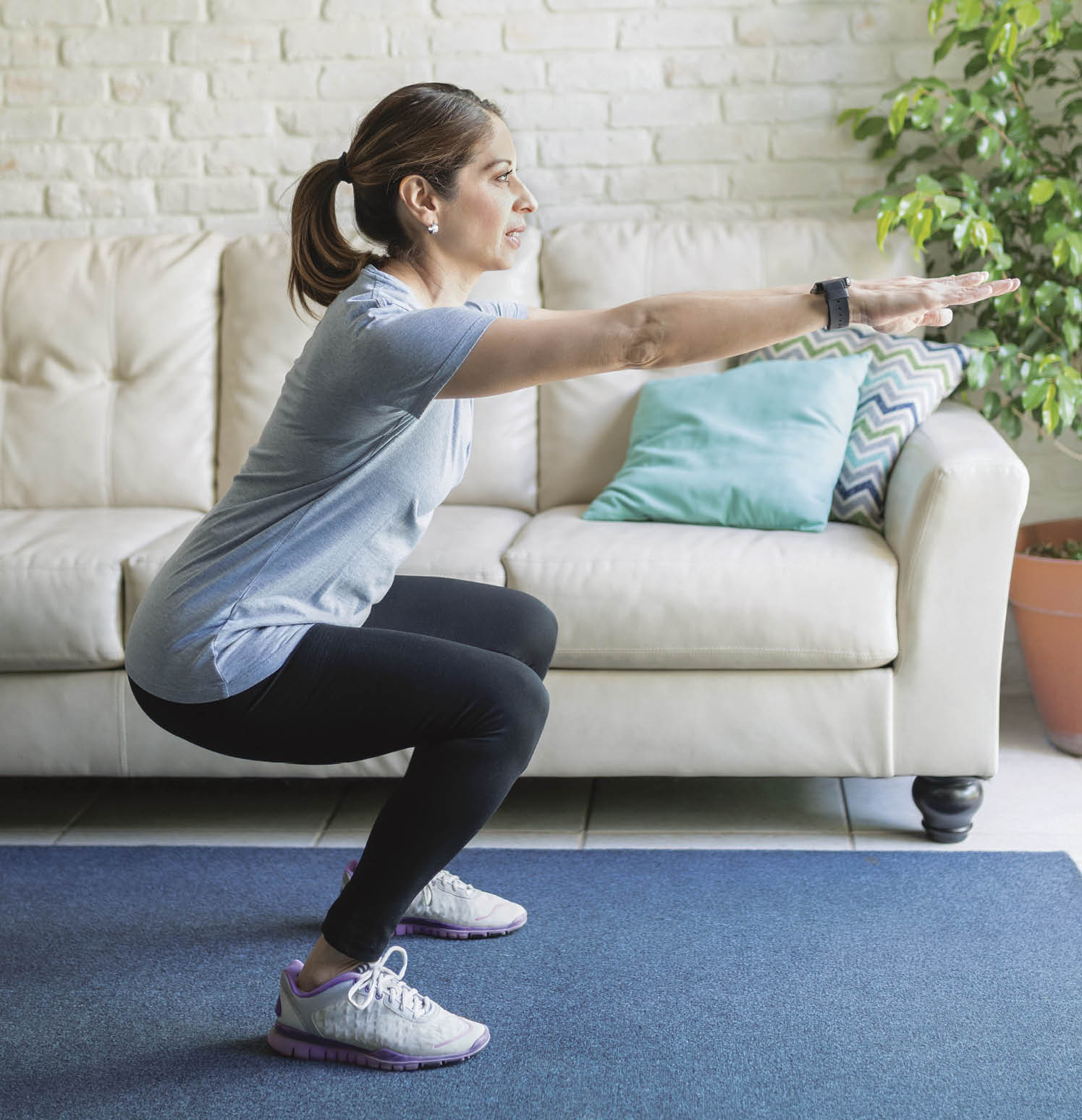 Full length view of an active woman in her 40s working out and doing some squats at home