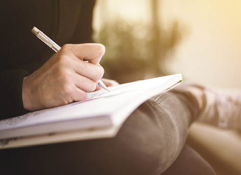 woman writing or scribbling on a notepad that is resting on her legs