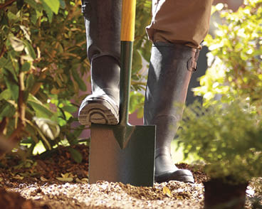 Cropped shot of feet digging a patch over with a garden trowel
