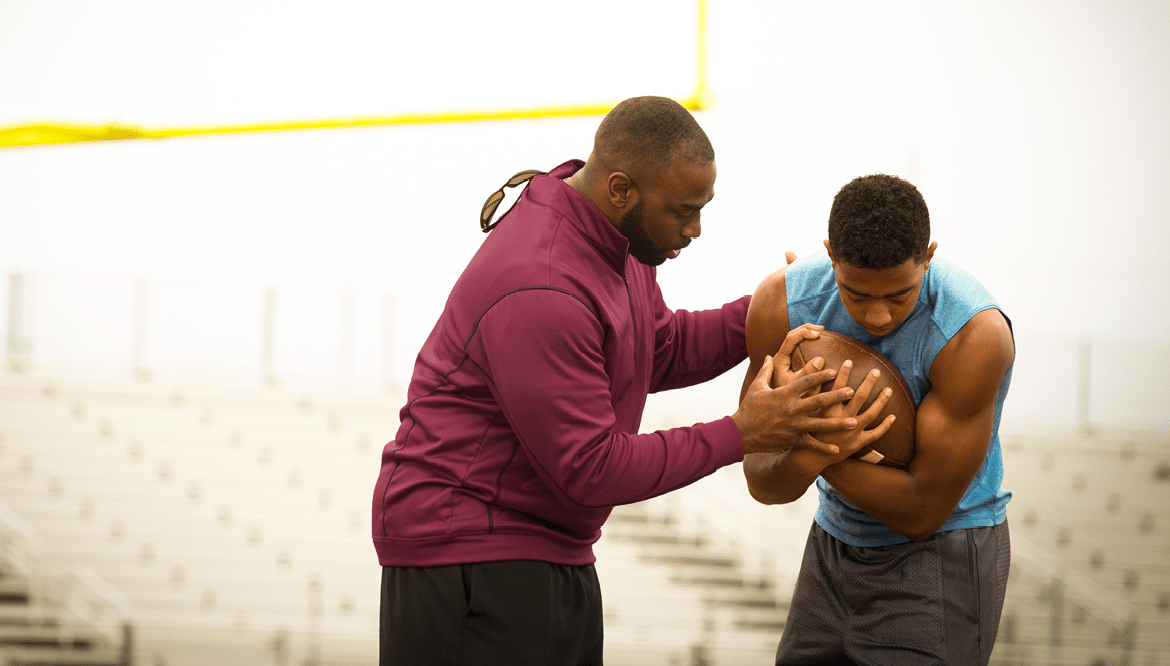 Coach giving tips to an athlete on football techniques 