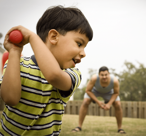Child playing tee ball with his father 