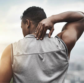 Rearview shot of a sporty young man touching his neck while exercising outdoors