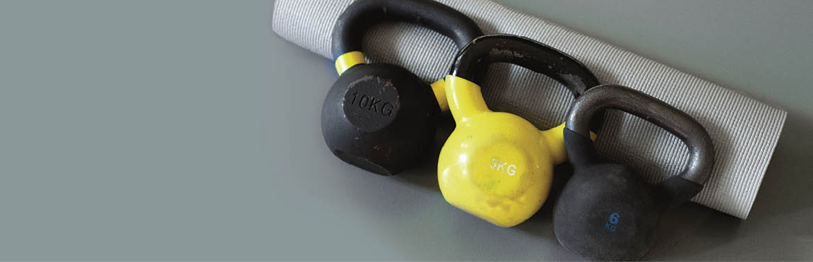 picture of three kettlebells with dummbells and yoga mat on the grey background