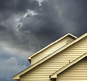 close up shot of yellow siding house over storm clouds 