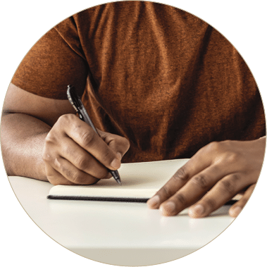 Image of happy African man with notepad and pen sitting on sofa 