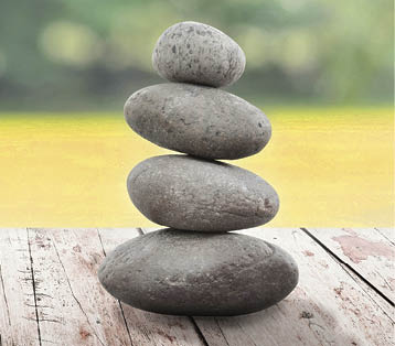 zen stones on wooden in the garden  vintage wood table in relaxing wellness holistic spa for relaxation and good health rejuvenation  stones stacked on wooden table outdoors 